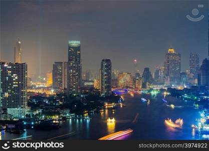 Aerial view of Chao Phraya River, Bangkok Downtown. Financial district and business centers in smart urban city in Asia. Skyscraper and high-rise buildings at night.