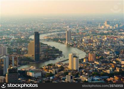 Aerial view of Chao Phraya River, Bangkok Downtown. Financial district and business centers in smart urban city in Asia. Skyscraper and high-rise buildings at sunset.