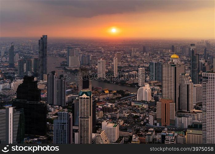 Aerial view of Chao Phraya River with the sun, Bangkok Downtown. Financial district and business centers in smart urban city in Asia. Skyscraper and high-rise buildings at sunset.