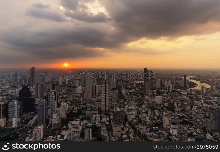 Aerial view of Chao Phraya River with the sun, Bangkok Downtown. Financial district and business centers in smart urban city in Asia. Skyscraper and high-rise buildings at sunset.