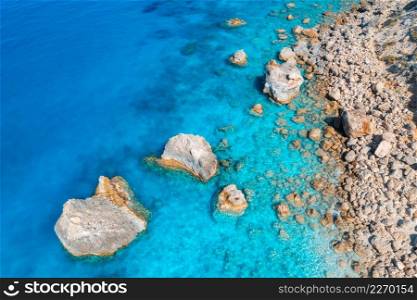 Aerial view of clear blue sea, stones and rocks in water, empty beach at sunset. Summer in Lefkada island, Greece. Tropical seascape with azure water. Top view of sea coast. Nature background. Travel