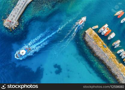 Aerial view of colorful boats and yachts in port in blue sea at sunset. Summer landscape with beautiful motorboats in harbor, pier, transparent water in Dubrovnik. View from above of harbour. Travel