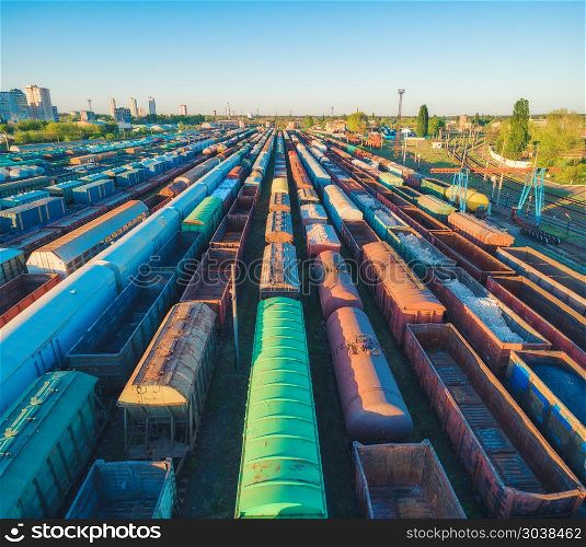 Aerial view of colorful freight trains. Cargo wagons on railway station. Wagons with goods on railroad. Heavy industry. Industrial landscape with train, railway platfform at sunset. Top view. Depot. Aerial view of colorful freight trains on railroad