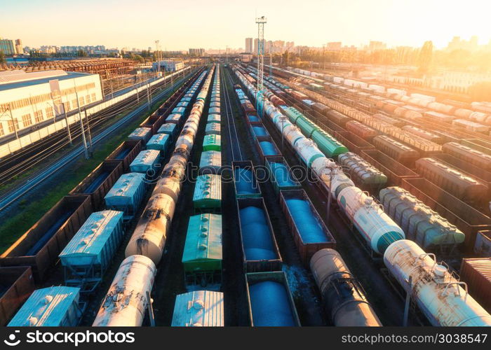 Aerial view of colorful freight trains. Cargo wagons on railway station. Wagons with goods on railroad. Heavy industry. Industrial landscape with train, railway platfform at sunset. Top view. Depot. . Aerial view of colorful freight trains on railroad