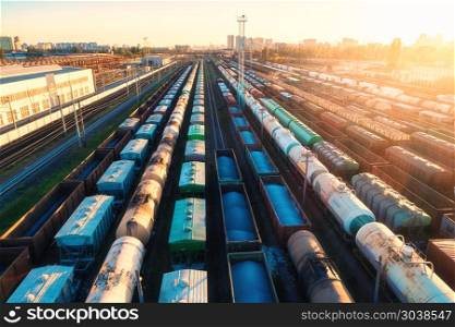 Aerial view of colorful freight trains. Cargo wagons on railway station. Wagons with goods on railroad. Heavy industry. Industrial landscape with train, railway platfform at sunset. Top view. Depot. . Aerial view of colorful freight trains on railroad