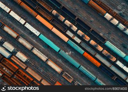 Aerial view of colorful freight trains on the railway station. Cargo trains close-up. Wagons with goods on railroad. Heavy industry. Industrial conceptual scene with trains. Top view. Vintage style. Aerial view of colorful freight trains