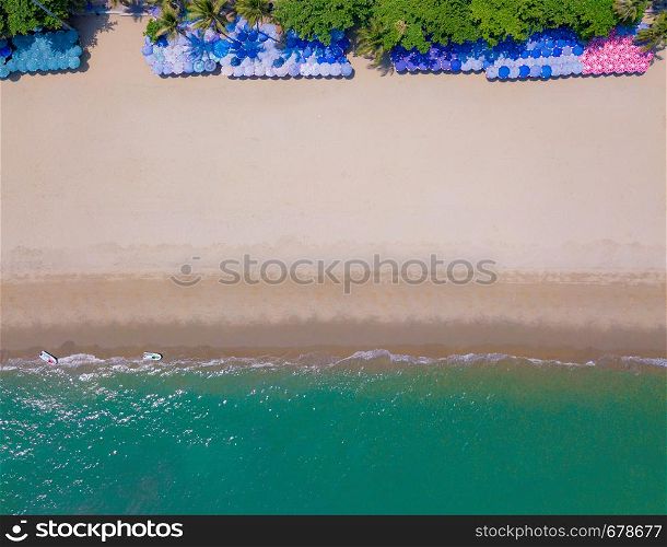 Aerial view of colorful umbrellas, beach, and turquoise sea with space for text. Sunny summer day for travel or holiday background in Pattaya, Chon Buri province, Thailand. Top view