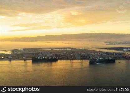 Aerial view of container cargo ship in the export and import business and logistics international goods in urban city. Shipping to the harbor by crane in Osaka Harbour, Japan