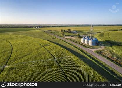 aerial view of corn field with sprinkler, silo, and farm buildings in eastern Colorado