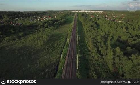Aerial view of countryside in Russia. Railway running through the village among green trees