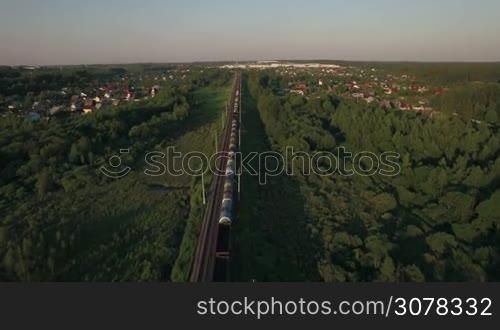 Aerial view of countryside with summer houses and freight train traveling through it, Russia
