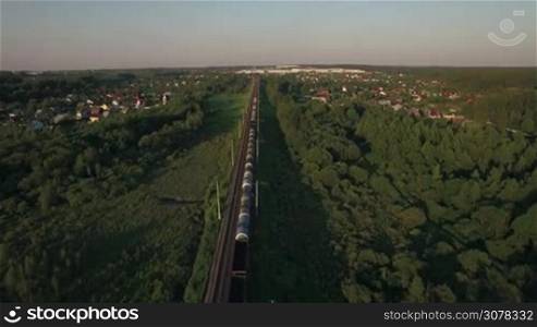 Aerial view of countryside with summer houses and freight train traveling through it, Russia