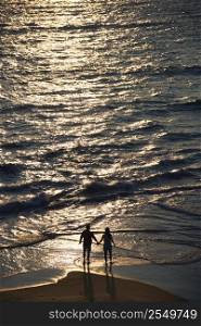 Aerial view of couple holding hands on beach in Bald Head Island, North Carolina at sunset.