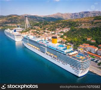 Aerial view of cruise ship in harbor. Top view of beautiful large ships and boats at sunny day. Landscape with harbour, city, buildings, mountains, blue sea. Luxury cruise. Floating liner in port