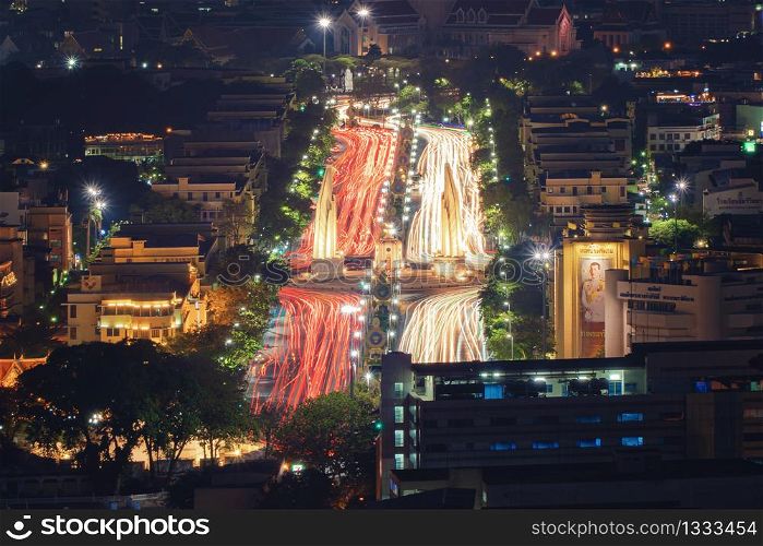 Aerial view of Democracy monument with car light trails on road in Bangkok Downtown, urban city at night, Thailand. Landmark architecture landscape background.