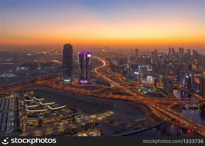 Aerial view of Dubai Downtown skyline and highway, United Arab Emirates or UAE. Financial district and business area in smart urban city. Skyscraper and high-rise buildings at night.