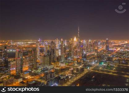 Aerial view of Dubai Downtown skyline, highway roads or street in United Arab Emirates or UAE. Financial district and business area in smart urban city. Skyscraper and high-rise buildings at night.