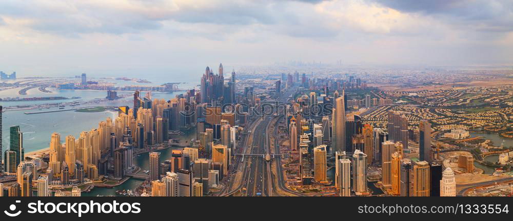 Aerial view of Dubai Downtown skyline, highway roads or street in United Arab Emirates or UAE. Financial district and business area in smart urban city. Skyscraper and high-rise buildings at sunset.