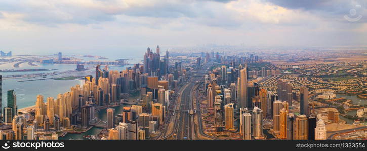 Aerial view of Dubai Downtown skyline, highway roads or street in United Arab Emirates or UAE. Financial district and business area in smart urban city. Skyscraper and high-rise buildings at sunset.