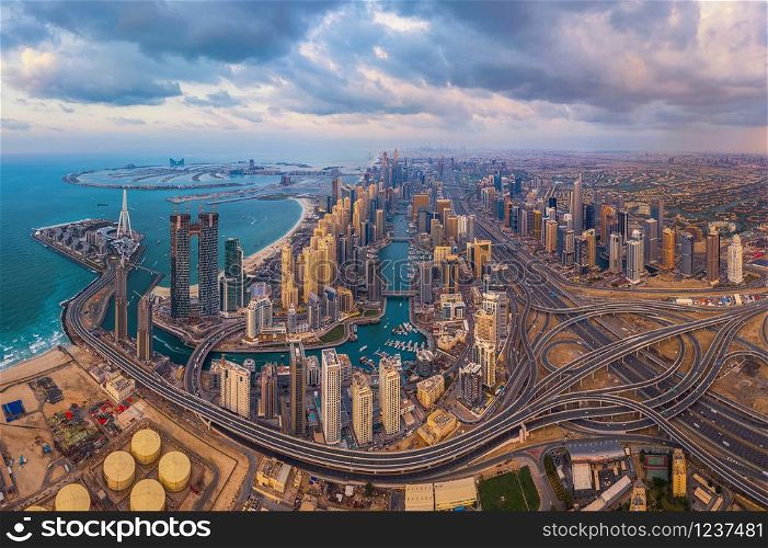 Aerial view of Dubai Marina and highways, Downtown skyline, United Arab Emirates or UAE. Financial district and business area in smart urban city. Skyscraper and high-rise buildings at sunset.