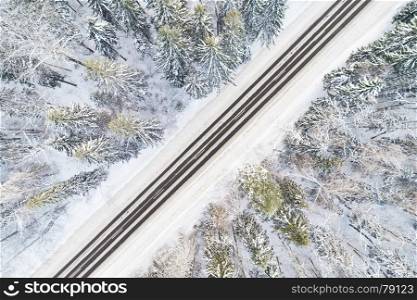 Aerial view of empty snow covered road in winter forest