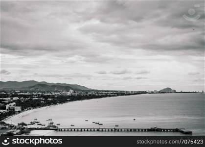 Aerial view of famous Hua Hin beach and bay in evening with cityscape. Thailand tropical beach destination in black and white.