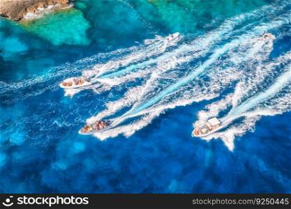 Aerial view of fast floating yachts and boats on blue sea at sunny day in summer. Sardinia, Italy. Aerial view of speed boats, sea lagoon, transparent azure water. Top drone view. Tropical seascape