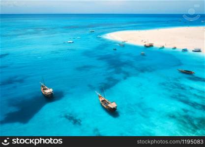 Aerial view of fishing boats on tropical sea coast with transparent blue water and sandy beach at sunny day. Summer holiday. Indian Ocean in Zanzibar, Africa. Landscape with boat, white sand. Top view