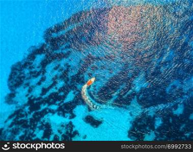 Aerial view of floating speed boat in transparent blue water. Motorboat in the sea in balearic islands at sunset in summer. Landscape. Top view from drone. Seascape with yacht in motion in bay