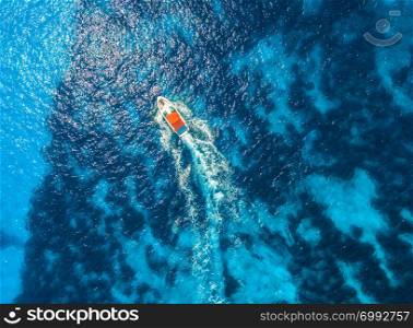 Aerial view of floating speed boat in transparent blue water. Motorboat in the sea in balearic islands at sunset in summer. Landscape. Top view from drone. Seascape with yacht in motion in bay