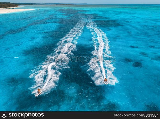 Aerial view of floating water scooter in blue water at sunny day in summer. Holiday in Indian ocean, Zanzibar, Africa. Top view of jet ski in motion. Tropical seascape with moving motorboat. Extreme