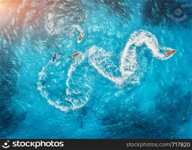 Aerial view of floating water scooter in blue water at sunset in summer. Holiday in Indian ocean, Zanzibar, Africa. Top view of jet ski in motion. Tropical seascape with moving motorboat. Extreme. Aerial view of floating water scooter in blue water at sunset