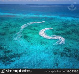 Aerial view of floating water scooter in clear blue water at sunny day in summer. Holiday in Zanzibar, Africa. Top view of jet ski in motion. Tropical seascape with moving motorboat. Extreme. Boats