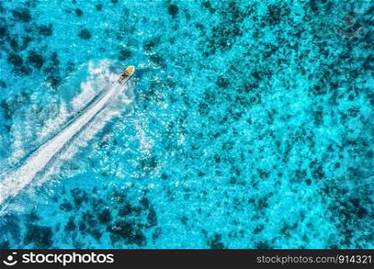 Aerial view of floating water scooter in transparent blue water at summer day. Holiday in Zanzibar, Africa. Top view of jet ski in motion. Tropical seascape with moving motorboat. Extreme. Boats