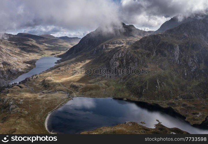 Aerial view of flying drone Epic early Autumn Fall landscape image of view along Ogwen vslley in Snowdonia National Park with dramatic sky and mountains