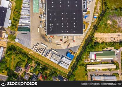 Aerial view of goods warehouse. Logistics delivery center in industrial city zone from above. Aerial view of trucks loading at logistic center. View from drone.