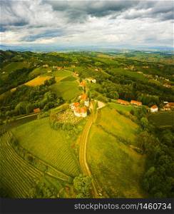 Aerial view of green hills and vineyards with mountains in background. Austria vineyards landscape. Leibnitz area in south Styria, wine country. Tuscany like place and famous tourist spot. Aerial view of of green hills and vineyards with mountains in background