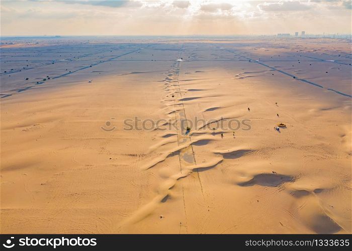 Aerial view of half desert road or street with sand dune in Dubai City, United Arab Emirates or UAE. Natural landscape background at sunset time. Famous tourist attraction. Top view.