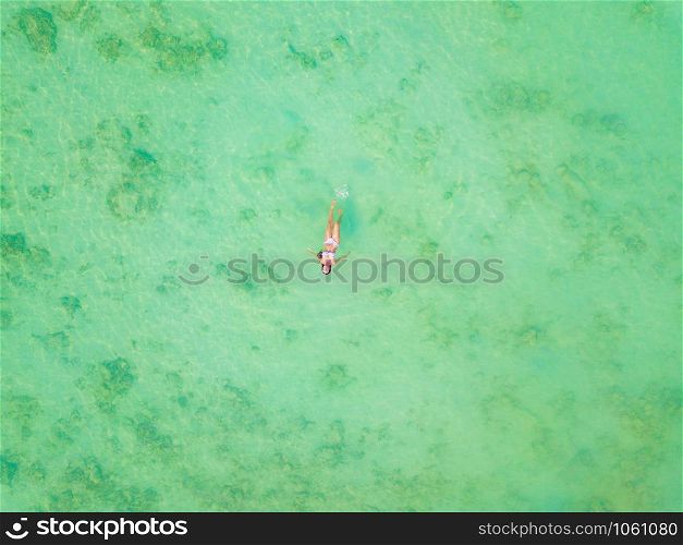 Aerial view of happy Asian woman, a sexy Thai lady, swimming at turquoise sea near Phuket beach in summer during travel holidays vacation trip outdoor at natural ocean or island, Thailand