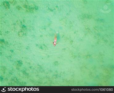 Aerial view of happy Asian woman, a sexy Thai lady, swimming at turquoise sea near Phuket beach in summer during travel holidays vacation trip outdoor at natural ocean or island, Thailand