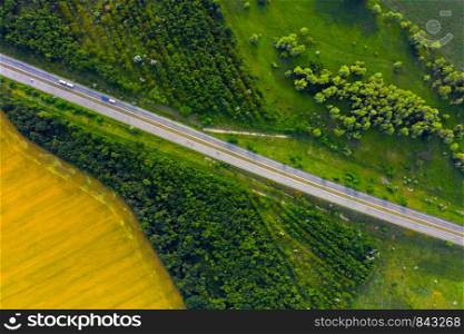 aerial view of highway going through the green and yellow summer fields