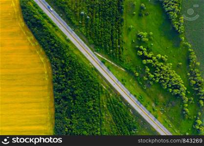 aerial view of highway going through the green and yellow summer fields