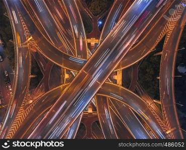 Aerial view of highway junctions shape letter x cross at night with fog. Bridges, roads, or streets in transportation concept. Structure shapes of architecture in urban city, Shanghai Downtown, China.