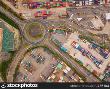 Aerial view of highway junctions with roundabout and containers. Bridge roads shape circle in structure in logistic transportation concept. Top view. Urban city, Hong Kong at noon, China.