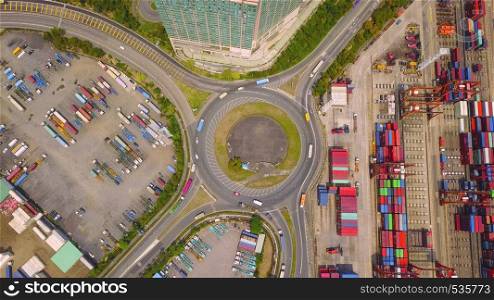Aerial view of highway junctions with roundabout and containers. Bridge roads shape circle in structure in logistic transportation concept. Top view. Urban city, Hong Kong at noon, China.