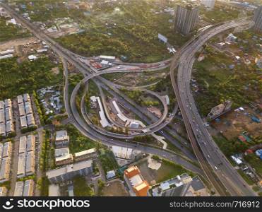 Aerial view of highway junctions with roundabout. Bridge roads shape circle in structure of architecture and transportation concept. Top view. Urban city, Bangkok at sunset, Thailand.