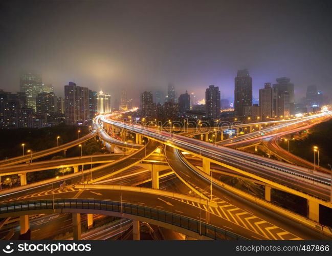 Aerial view of highways in Shanghai Downtown, China. Financial district and business centers in smart city in Asia. Top view of skyscraper and high-rise buildings at night.