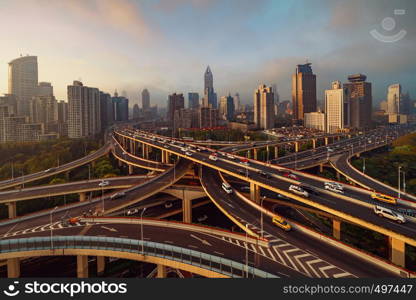 Aerial view of highways in Shanghai Downtown, China. Financial district and business centers in smart city in Asia. Top view of skyscraper and high-rise buildings at sunset.