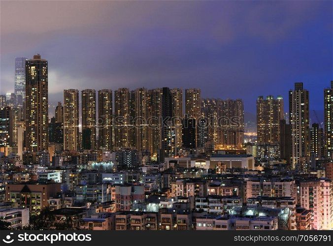 Aerial view of Hong Kong apartments and mountain in cityscape background. Residential district in smart city in Asia. Buildings at night.