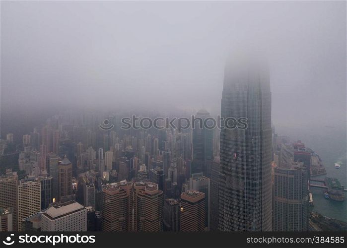 Aerial view of Hong Kong Downtown and Victoria Harbour with rain storm and fog. Financial district and business centers in smart city and technology concept. skyscraper and high-rise office buildings